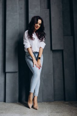 Stüdyoda poz veren kot pantolonlu ve gömlekli esmer kadın. 