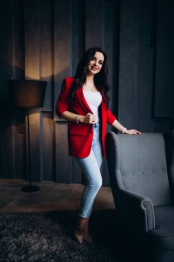 Kırmızı ceketli güzel, genç esmer kadın lambanın yanında poz veriyor. 