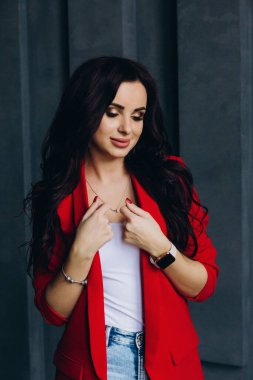 Kırmızı ceketli güzel esmer kadın odada poz veriyor. 