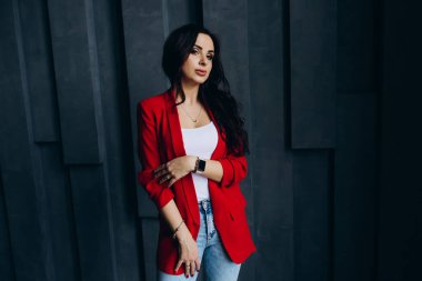 Kırmızı ceketli güzel esmer kadın odada poz veriyor. 