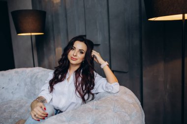 Stüdyoda gri koltukta poz veren güzel esmer kadın.