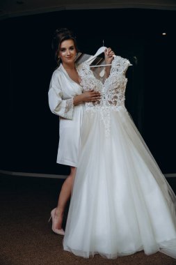 Güzel mutlu genç gelinin portresi zarif bir gelinlik tutuyor.          