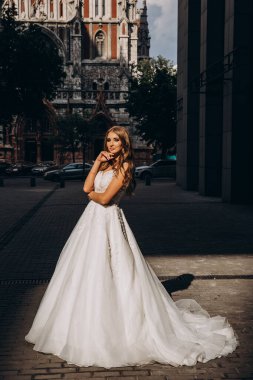 Beyaz gelinlikli güzel gelin şehirde poz veriyor.             