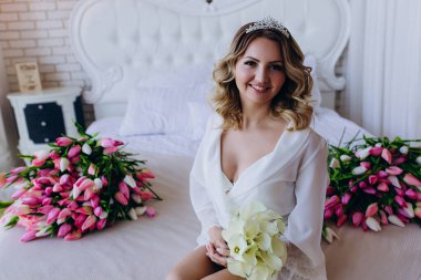 Çiçeklerle dolu yatakta oturan güzel gelin. 