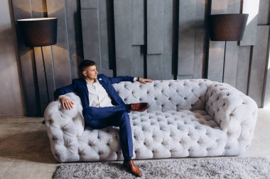 Koltukta oturan takım elbiseli yakışıklı bir iş adamının portresi.