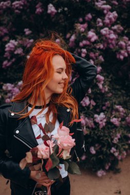 Parkta çiçek açan ağaca poz veren güzel kızıl saçlı kız.