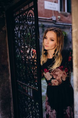 Eski binanın yanında poz veren güzel sarışın bir kadının portresi..