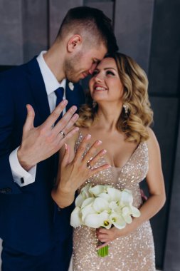 Mutlu gelin ve damat alyanslarıyla stüdyoda poz veriyor..