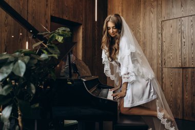 İpek bornoz ve peçeli güzel gelin piyano çalıyor.
