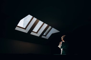 Beyaz cüppeli çekici bir kadın karanlık odada dikiliyor.    