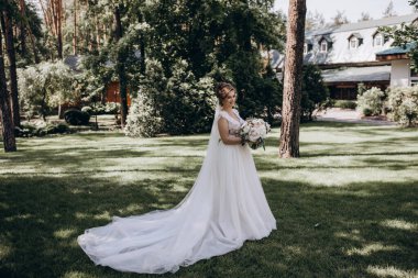 Gelinlik içinde güzel bir buket çiçek taşıyan muhteşem genç gelinin portresi.              