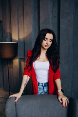 Kırmızı ceketli güzel, genç esmer kadın lambanın yanında poz veriyor. 