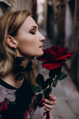 Bulanık arka planda gülleri olan genç bir kadın. 