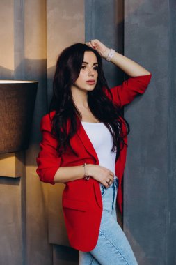 Kırmızı ceketli güzel, genç esmer kadın lambanın yanında poz veriyor. 