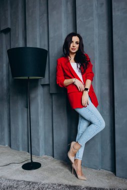 Kırmızı ceketli güzel, genç esmer kadın lambanın yanında poz veriyor. 