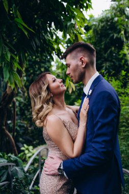 Güzel genç gelin ve damat bahçede sarılıyor.