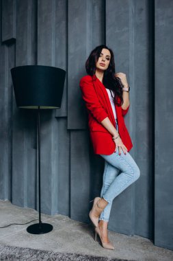 Kırmızı ceketli güzel, genç esmer kadın lambanın yanında poz veriyor. 