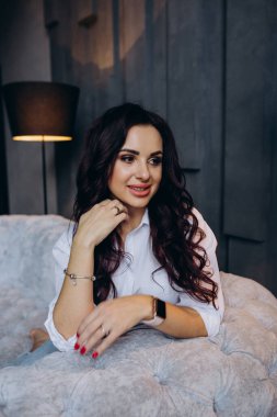 Stüdyoda gri koltukta poz veren güzel esmer kadın.