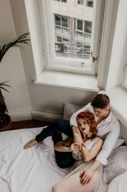 Yatakta sarılan genç çiftin yüksek açılı görüntüsü.