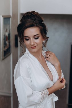 Beyaz bornozlu güzel gelinin portresi. Düğün sabahı evde.       