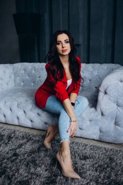 Kırmızı ceketli güzel, genç esmer kadın lambanın yanında poz veriyor. 