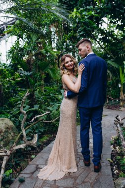 Genç çift botanik parkında birbirlerine sarılıp poz veriyorlar. 