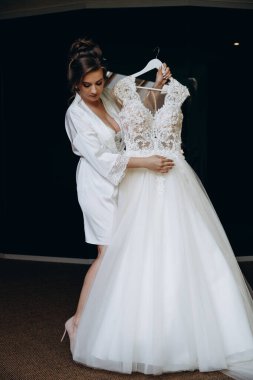 Güzel mutlu genç gelinin portresi zarif bir gelinlik tutuyor.          