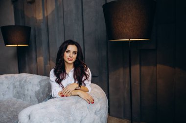 Stüdyoda gri koltukta poz veren güzel esmer kadın.