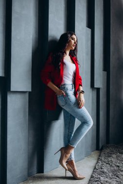 Kırmızı ceketli güzel esmer kadın odada poz veriyor. 