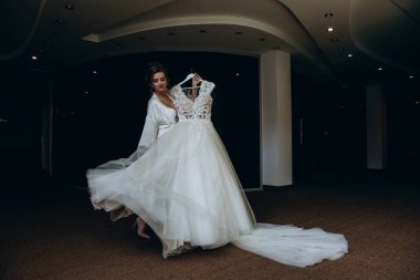 Güzel mutlu genç gelinin portresi zarif bir gelinlik tutuyor.          