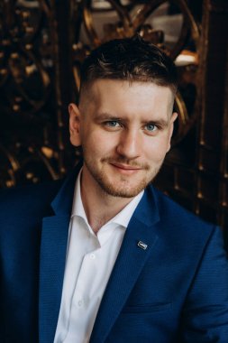 Klasik takım elbiseli genç, zarif iş adamı otel odasının içinde poz veriyor..