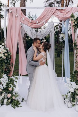 Düğün kemerinin yanında poz veren mutlu gelin ve damat parktaki düğün töreninde            