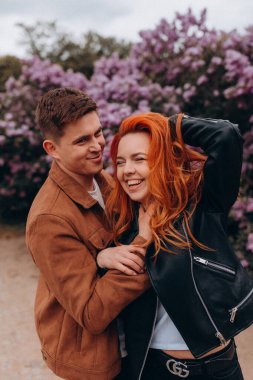 Bir çift genç adam ve güzel kadın parkta poz veriyor, gülümsüyor, birlikte eğleniyorlar.