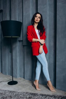 Kırmızı ceketli güzel, genç esmer kadın lambanın yanında poz veriyor. 