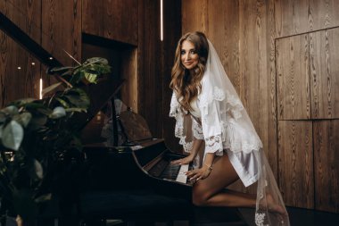 İpek bornoz ve peçeli güzel bir gelin piyano çalıyor.
