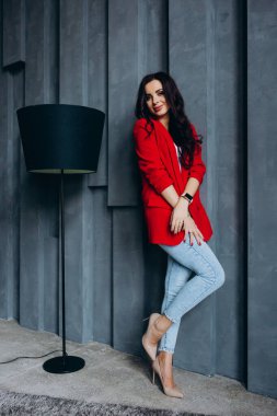 Kırmızı ceketli güzel, genç esmer kadın lambanın yanında poz veriyor. 