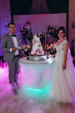 Mutlu gelin ve damat düğün gününü kutluyor ve düğün pastasını kesiyor.           