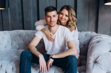 Genç çift evde, koltukta poz veriyorlar. 
