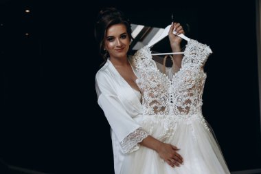 Güzel mutlu genç gelinin portresi zarif bir gelinlik tutuyor.          