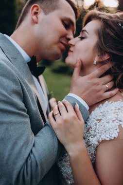 Mutlu gelin ve damat parkta öpüşüyor.