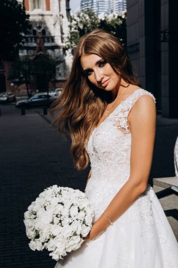 Beyaz gelinlikli güzel gelin şehirde poz veriyor.             