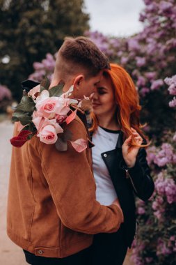 Genç ve güzel bir çift çiçek açan çalılara karşı poz veriyor. 