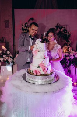 Mutlu gelin ve damat düğün gününü kutluyor ve düğün pastasını kesiyor.           