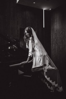 İpek cüppeli ve peçeli güzel gelin piyano çalıyor, siyah beyaz 