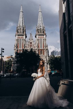 Beyaz gelinlikli güzel gelin şehirde poz veriyor.             