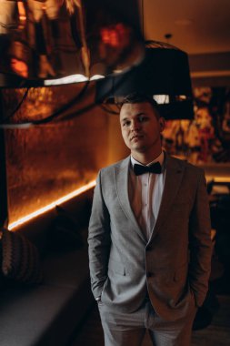 Beyaz gömlekli, papyonlu ve şık takım elbiseli genç damat.