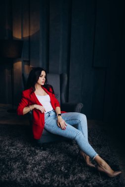 Kırmızı ceketli güzel, genç esmer kadın lambanın yanında poz veriyor. 