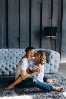 Genç çift evde, kanepenin yanında poz veriyorlar. 