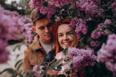 Genç çift parkta sarılıp öpüşüyor. 