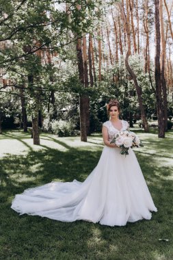 Gelinlik içinde güzel bir buket çiçek taşıyan muhteşem genç gelinin portresi.              